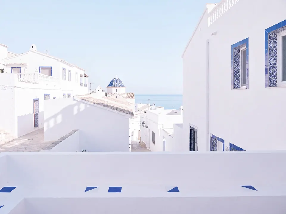 Tejados blancos y cúpula de azulejos azules sobre el mar en Altea